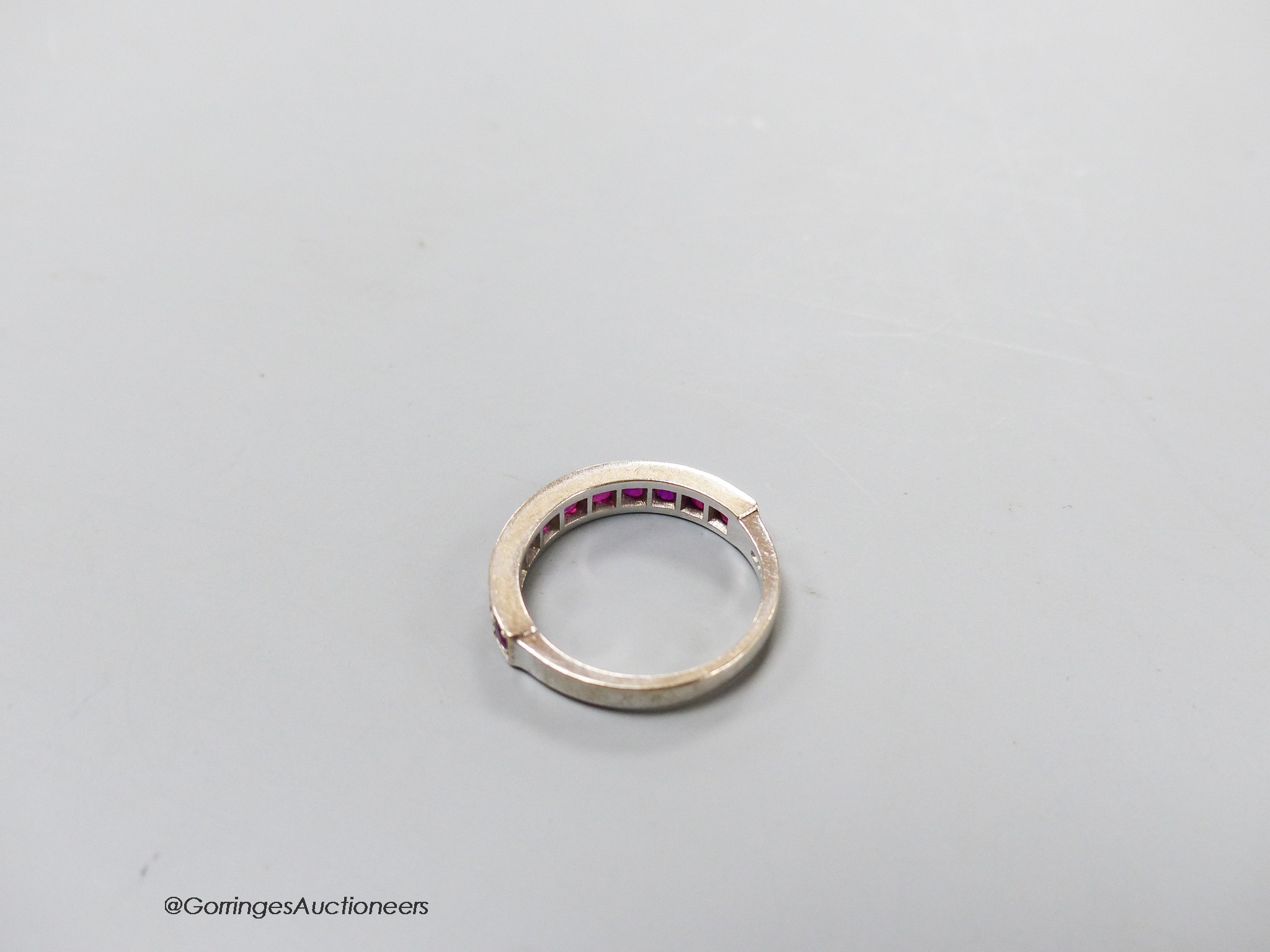 A modern 18ct white gold and eleven stone ruby set half eternity ring, size L, gross 3.7 grams.